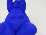 blue sculpture of a woman sitting on her stomach with her hands in the air