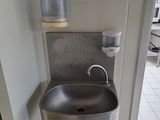 a stainless steel sink in the corner of a bathroom