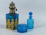 une bouteille en verre bleu ornée d'un motif doré et un récipient en verre bleu