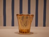 a glass vase sitting on a table with a striped wall behind it