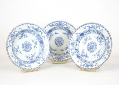 trois assiettes bleues et blanches à bordure dorée sur fond blanc