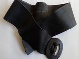 collier en cuir noir muni d'une boucle métallique, sur fond blanc