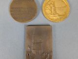 two gold medals and a silver medal on a blue surface