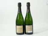deux bouteilles de champagne posées l'une à côté de l'autre sur une surface blanche
