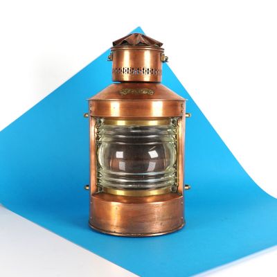 une petite lanterne en cuivre posée sur un papier bleu