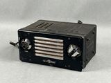 une radio noire posée sur une table, sur fond blanc