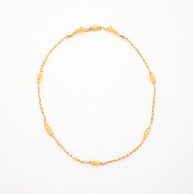 un bracelet en chaîne d'or orné d'une perle dorée sur fond blanc