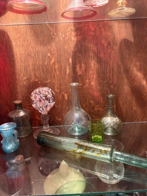 une étagère en verre sur laquelle sont posées des bouteilles et des vases en verre