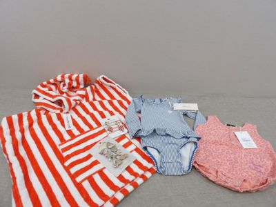 Plusieurs vêtements de bébé sont disposés les uns à côté des autres sur le sol.
