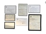 several old letters are displayed on a white wall with a black frame