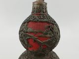 a red vase with a bird on it on a table