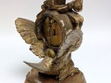 a gold clock with a bird on top of it