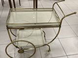 a glass and brass bar cart in the middle of a room