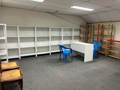 a room with a desk, shelves, and chairs in it