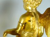 a gold statue of an angel with a clock in the background