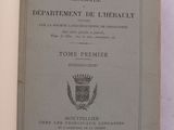 un livre ouvert posé sur une table, sur laquelle figure une image représentant des armoiries