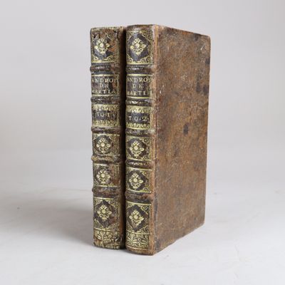 un vieux livre à la reliure dorée et noire posé sur une surface blanche