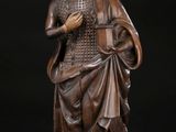 une statue ancienne en bois représentant une femme tenant un panier