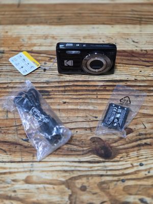 a small camera sitting on a wooden table next to other items