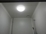 une lampe allumée au-dessus des toilettes dans une salle de bains