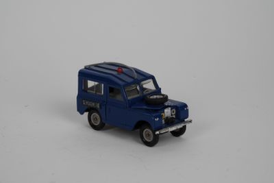 un petit camion bleu posé sur une surface blanche