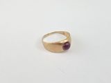 a close up of a gold ring with a red stone