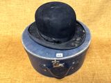 un chapeau noir posé sur une vieille valise