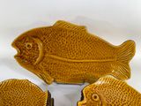 three ceramic fish shaped dishes on a white surface