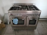 a stainless steel stove with two ovens and a blue towel on the floor