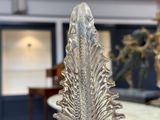 une sculpture en verre représentant une feuille, posée sur une table en marbre