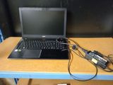 un ordinateur portable posé sur un bureau, avec son chargeur