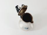 a small silver pitcher with a black handle on a white surface