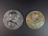 deux médaillons en bronze représentant un homme et une femme sur un fond noir