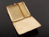 an antique gold cigarette case on a black surface