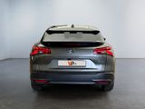 the rear end of a grey car in a white room