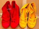 deux paires de chaussures rouges et jaunes posées sur une boîte en carton