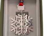 silver snowflake ornament in a gift box with a red ribbon