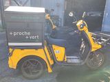 a yellow scooter with a box on the back parked in front of a building