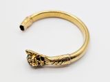 a close up of a gold bracelet with a skull on it