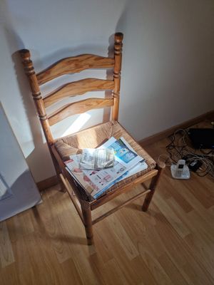 a wooden chair with a newspaper on it in the corner of a room