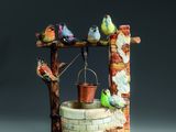 une figurine représentant un puits orné d'oiseaux