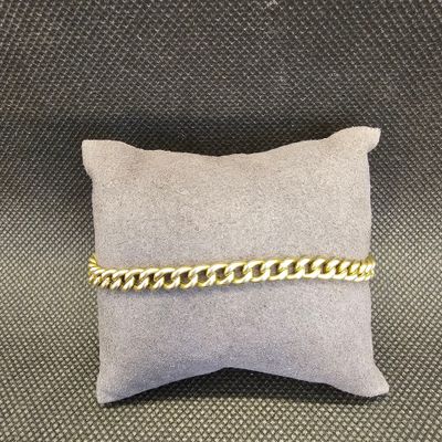 un bracelet en chaîne d'or posé sur un oreiller