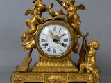 une horloge en or ornée d'anges, posée sur une table