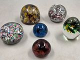 six billes de verre posées sur une surface blanche