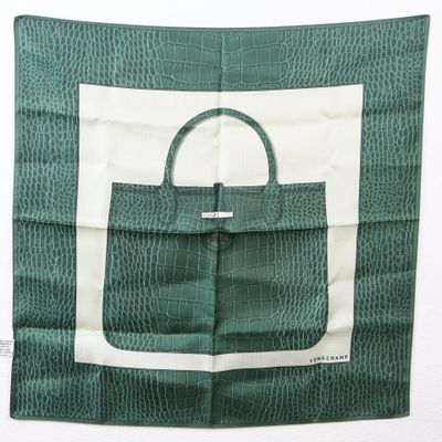 un sac à main vert et blanc posé sur un foulard vert et blanc