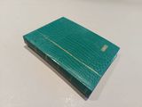 an open green book sitting on top of a white table