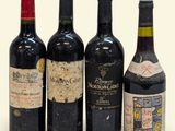 quatre bouteilles de vin sont alignées sur une surface blanche