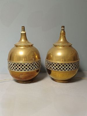 une paire de vases en laiton posés sur une surface blanche, avec un mur bleu en arrière-plan