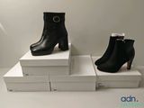 deux paires de bottines en cuir noir posées sur des cartons