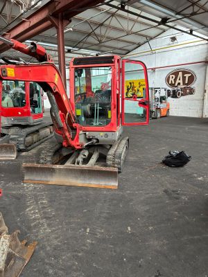 une pelleteuse rouge qui se trouve à l'intérieur d'un bâtiment